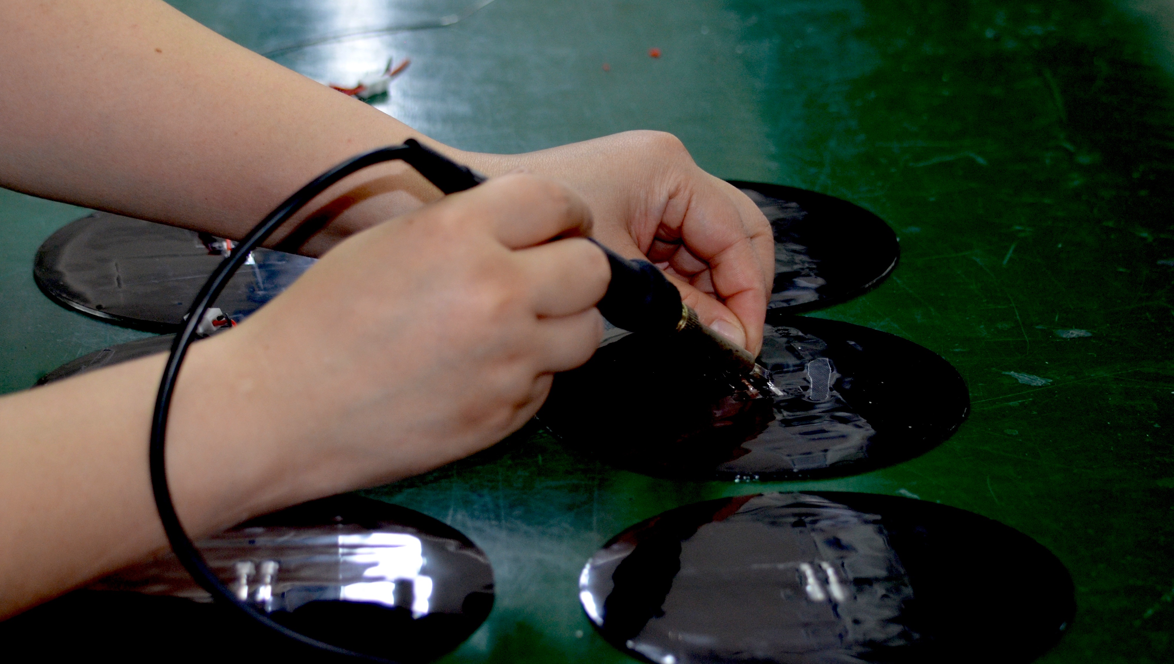 Hands completing wiring and soldering inside circular solar product housings